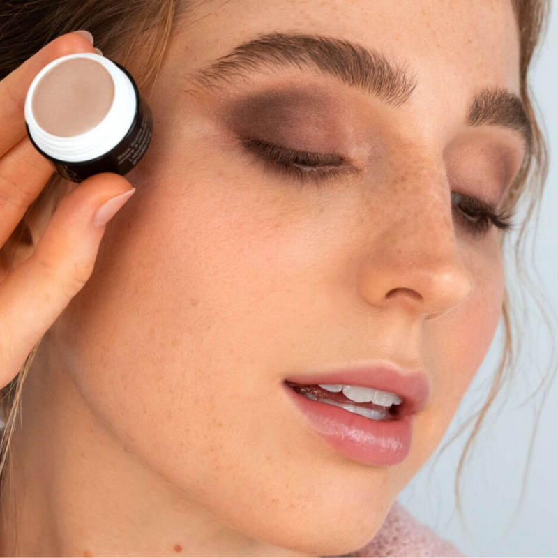 A woman with reddish hair is holding the ARTDECO Eyeshadow Base and showing off her beautifully made-up eyes.