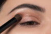 An eyeshadow brush is being used to apply eyeshadow on the lid