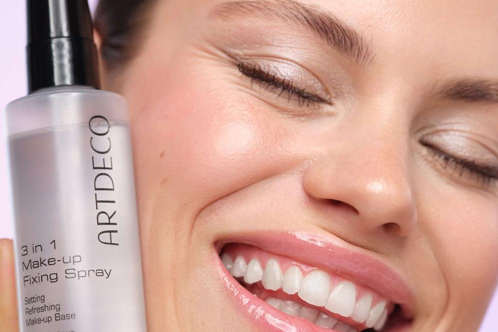 Model holds the 3 in 1 Make-up Fixing Spray to her cheek and smiles happily