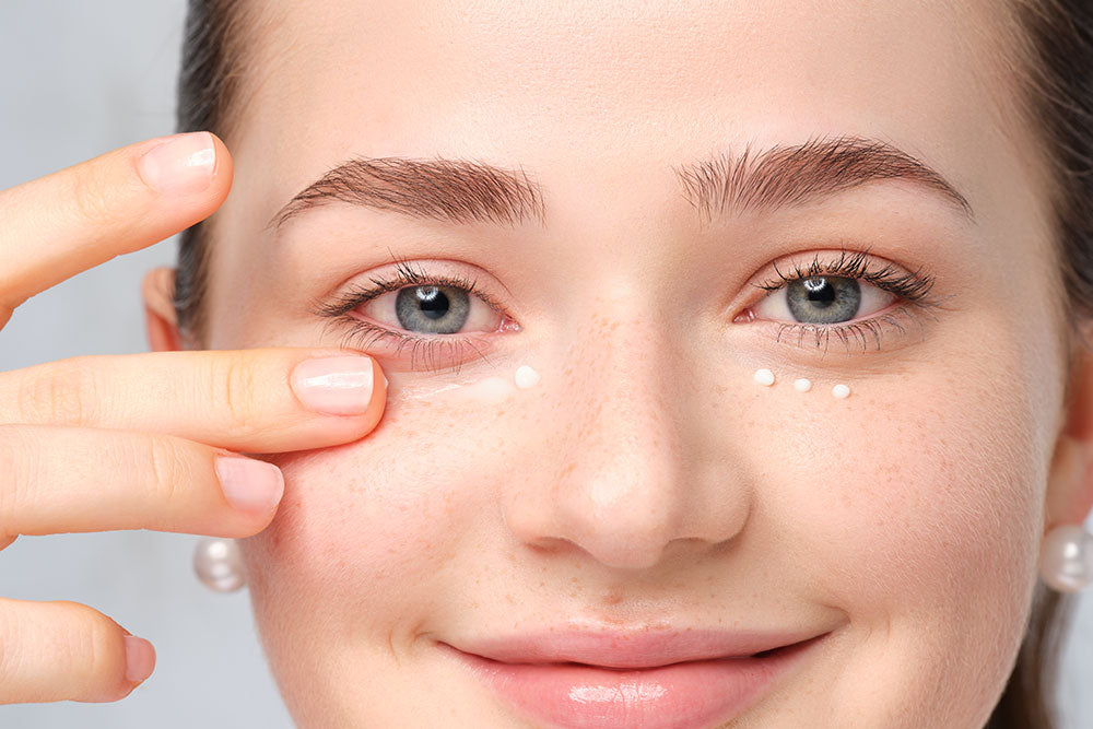 A female person applies a cream under her eyes