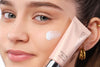 A primer is held in front of a female face
