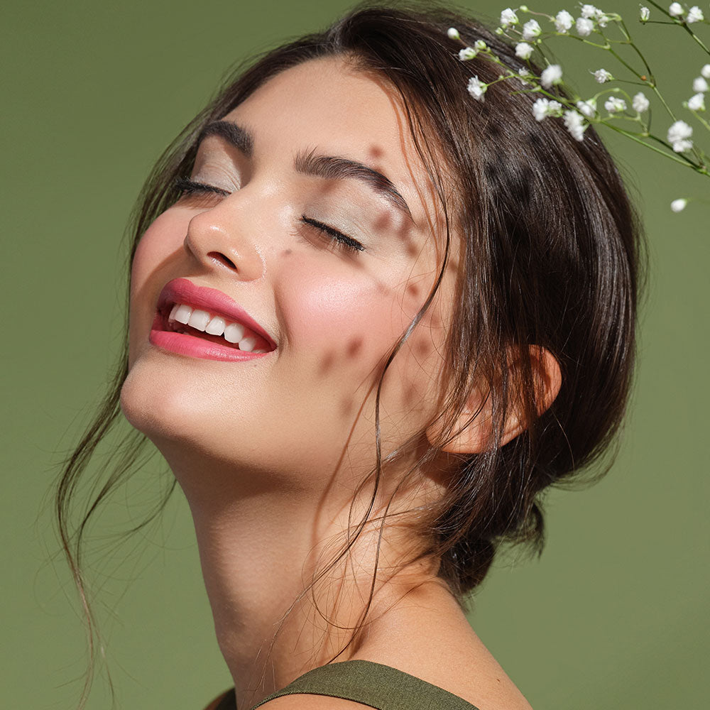 A smiling woman with her eyes closed, wearing makeup from the natural Green Couture product line