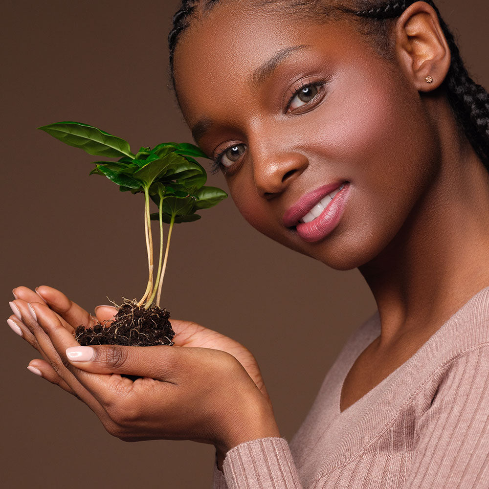 A woman is holding a small plant in her hands