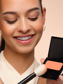 Model picks up pigments of a blusher with a blusher brush