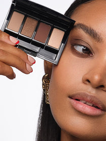 Close up of the model’s face, with a focus on the eyes, holding a Beauty Box filled with the eyeshadows used in the look