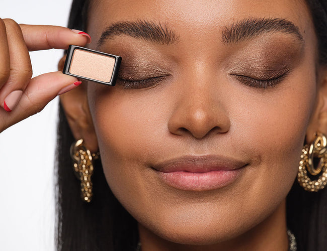 Close-up of closed eyelid with a light shimmery eyeshadow held against it