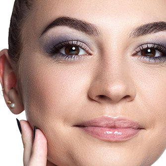 A model wearing makeup looks into the camera and smiles.