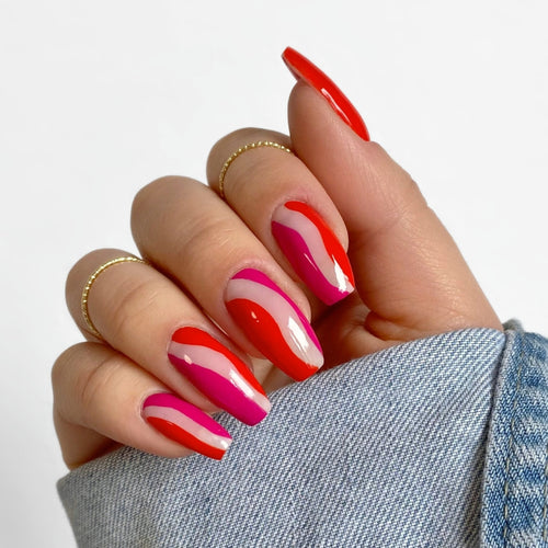 Finished nail design with red and pink wave pattern in a denim jacket
