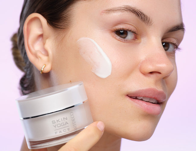 The model seen in profile, with the face cream product swatch on her cheek