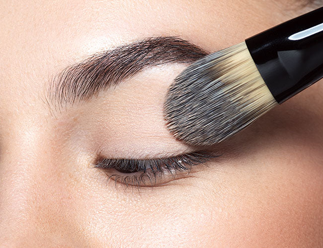Foundation is applied to the eye using a makeup brush.
