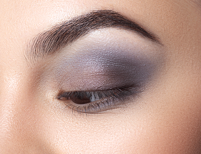 Dark eggplant-colored eyeshadow is applied along the upper lash line and blended upward toward the eyebrow.