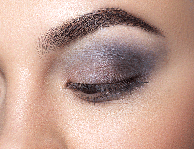 Light pink eyeshadow is applied with a compact brush to the inner corner of the eye and blended towards the center of the eye.