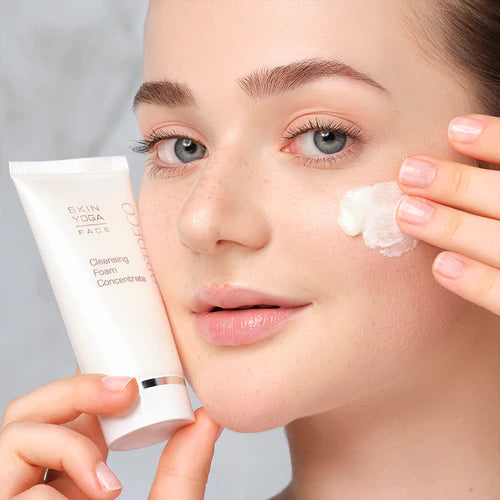 Model holding skin care product and applying it to cheek with one hand