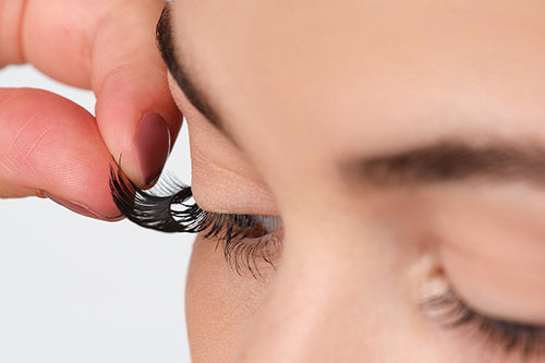 A woman is put artificial eyelashes on the natural eyelashes
