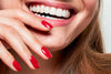 A hand with red painted nails is held in front of a laughing mouth