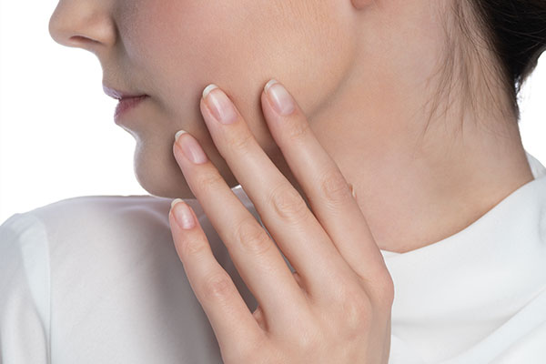 Unpainted nails are shown in front of a cheek