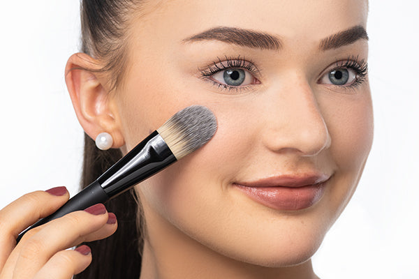 A face brush is being used to apply foundation on the face
