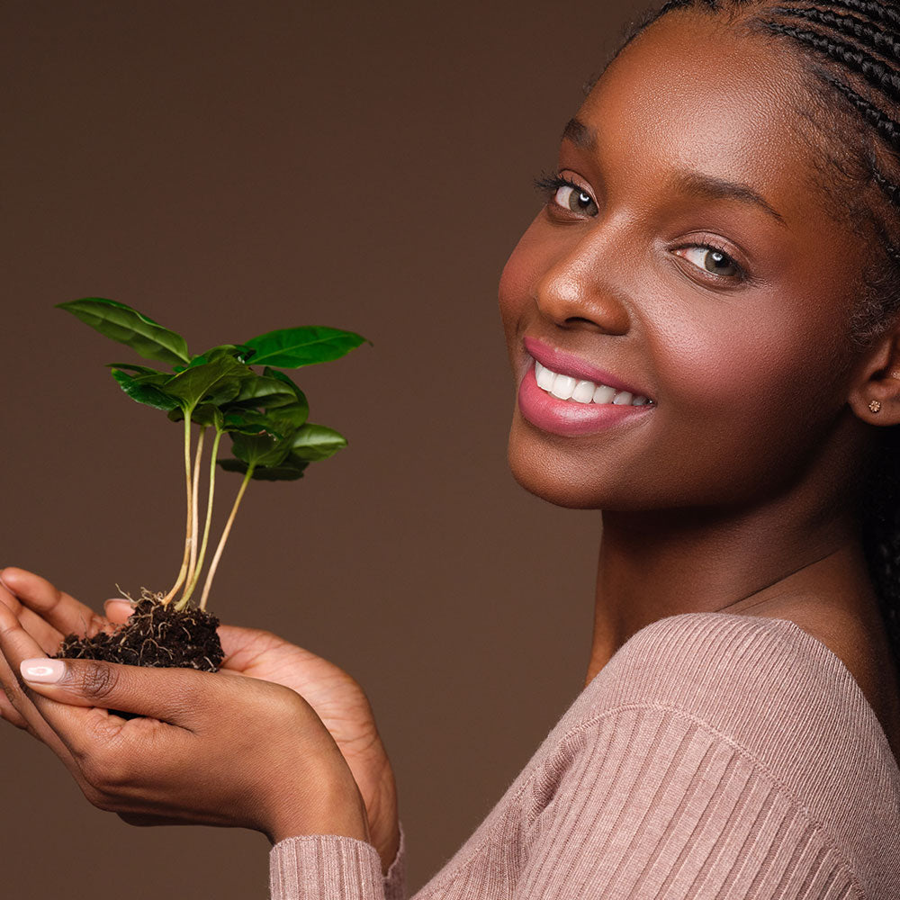 A smiling woman holding a plant shoot in her hand