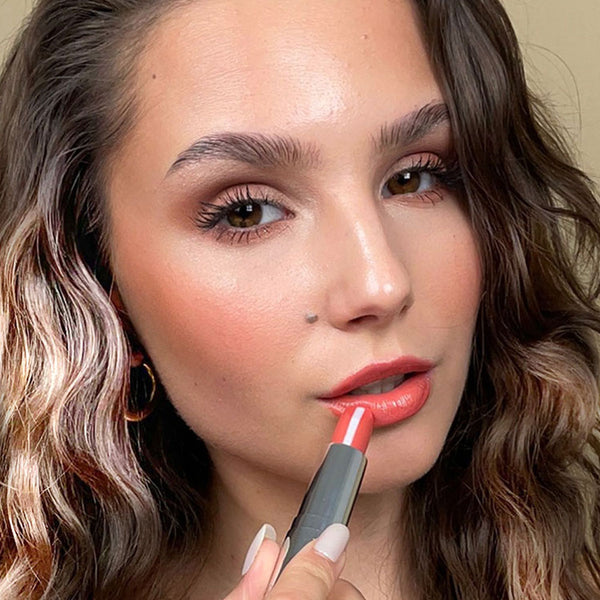 Model with summer make-up look. She holds the Hydra Care Lipstick to her lips.