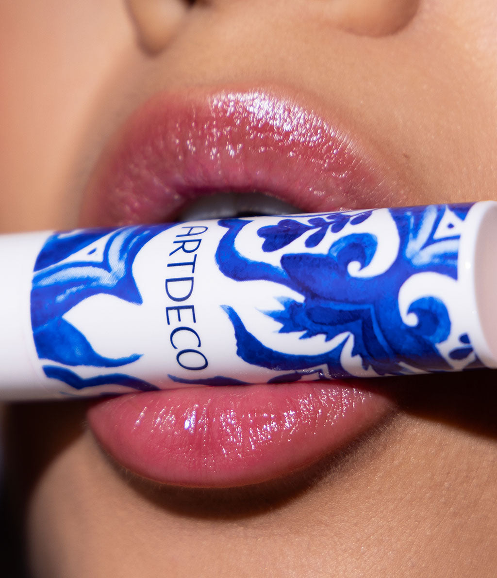 Close-up of the lips of the model, who presents the Color Booster Lip Balm in the gorgeous limited edition tile design between her lips