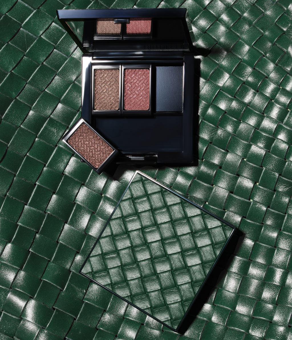 A limited-edition beauty box featuring the Intrecciato design, set against a background in the same design and filled with the three eyeshadows from the collection.