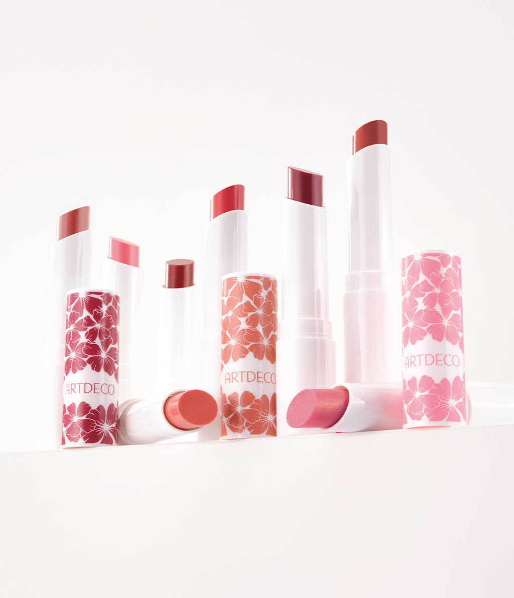 All eight shades of the Color Booster Lip Balm, featuring a limited-edition floral design, are beautifully displayed against a white background.