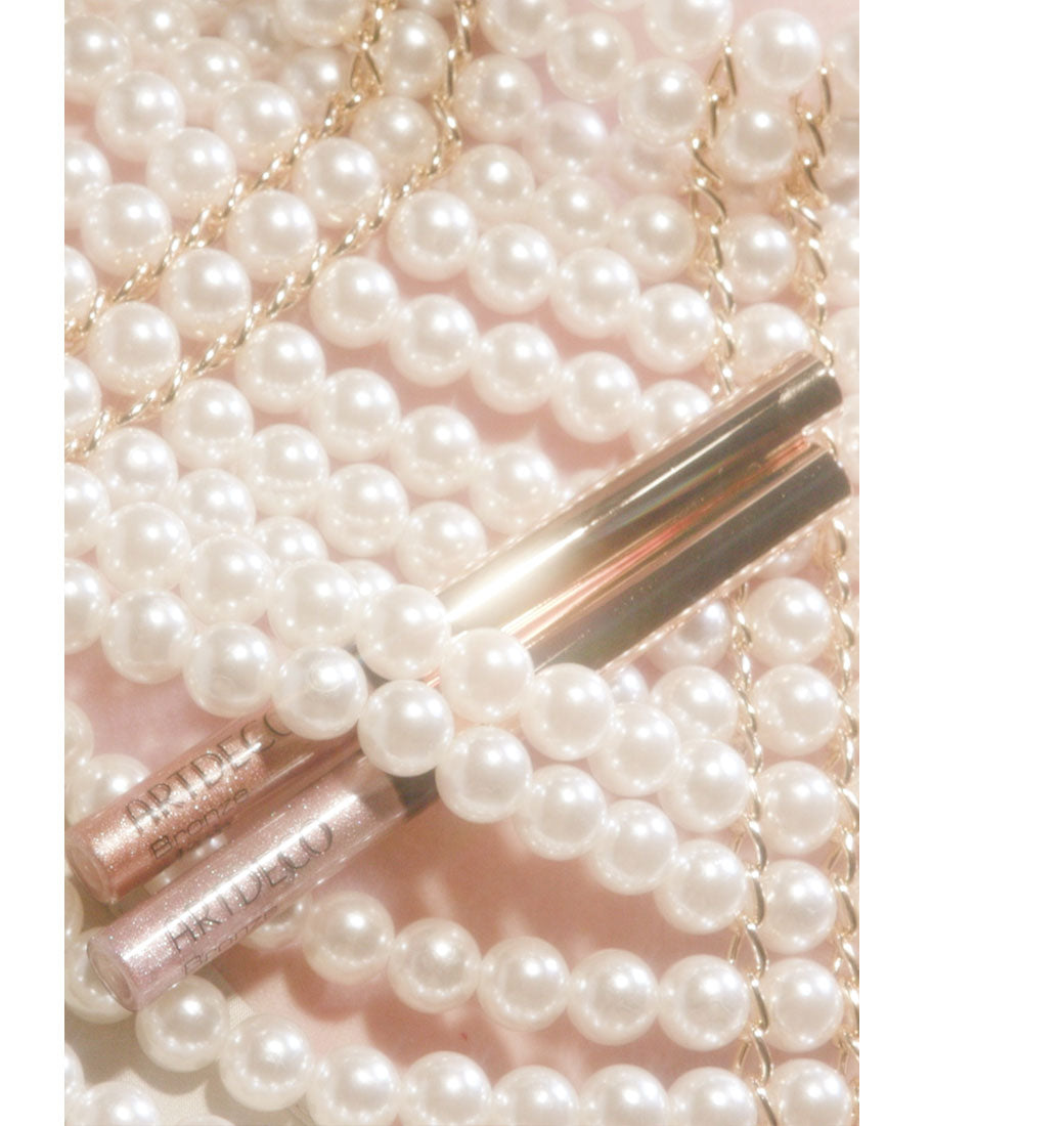 The two new Bronze Glam Eye Liners from the Mermaid Kiss Collection are beautifully placed behind some shimmering pearls. 