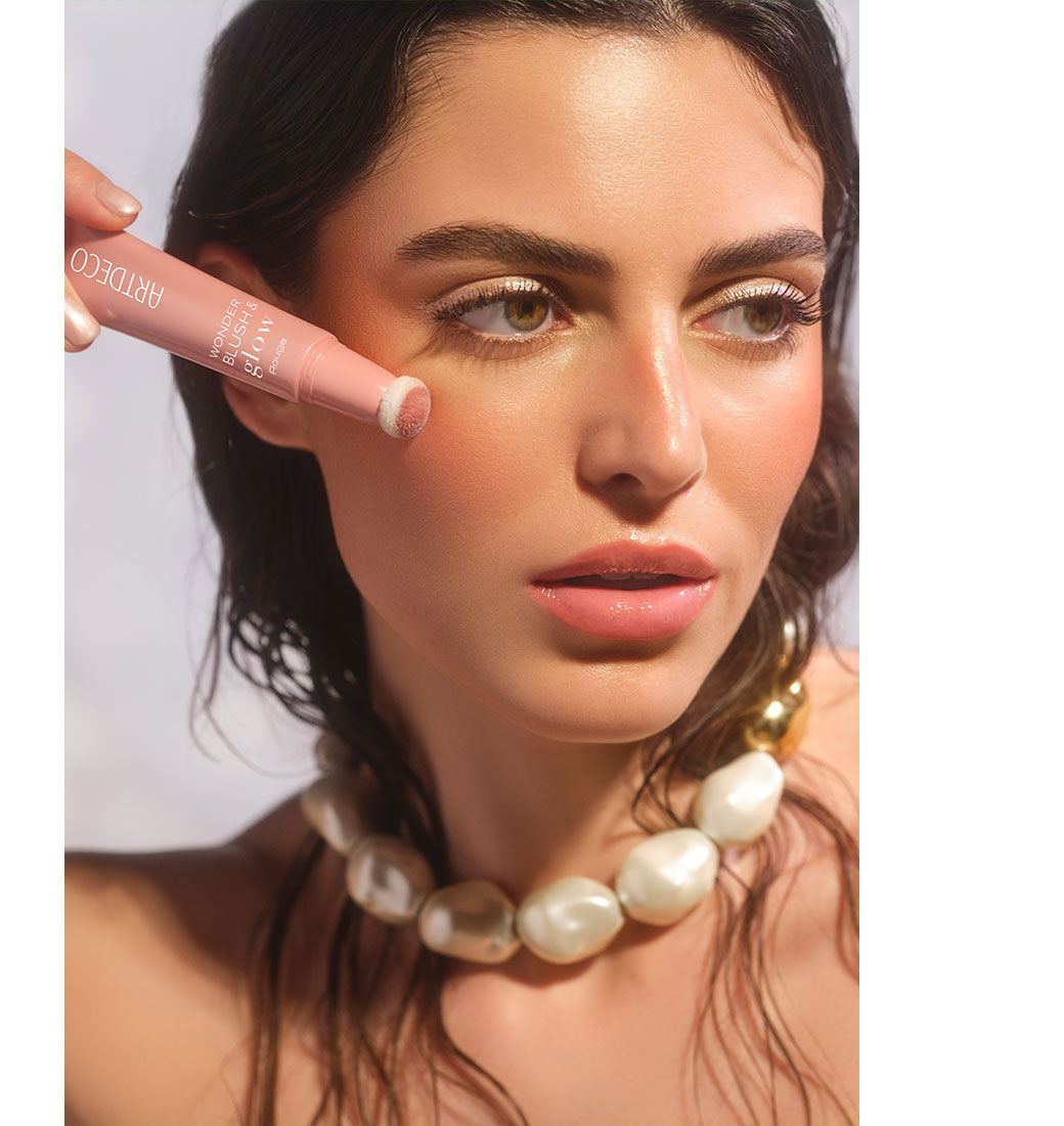 Brunette model applies Wonder Blush & Glow Rouge to her cheek with the sponge applicator to create a fresh, natural, glowing complexion.