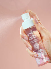 Hydrating Body Mist with a delicate cherry blossom fragrance is sprayed and the fine spray mist is clearly visible