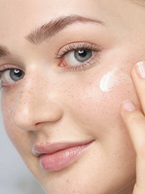 A model uses her fingers to apply Hyaluronic Intensive Serum to her cheek