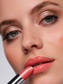 Close-up on model's face, focusing on lips holding apricot colored lipstick