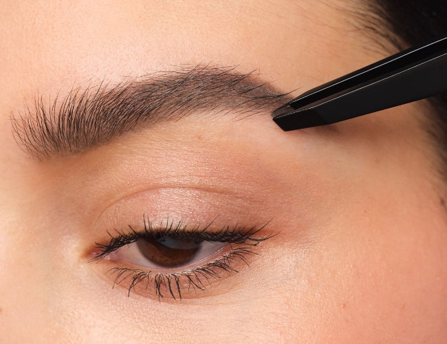 Eyebrows being plucked with tweezers.