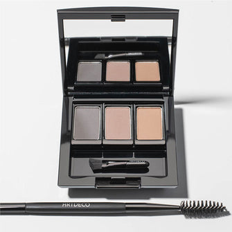 A Beauty Box Trio filled with three different Eye Brow Powders and an Eye Brow Brush. A 2 In 1 Brow Perfector sits next to the box.
