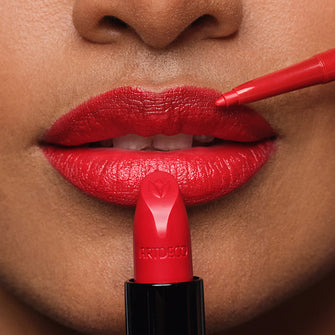 Close-up of the model’s lips with makeup applied and a red lipstick, with a lip liner held up to them