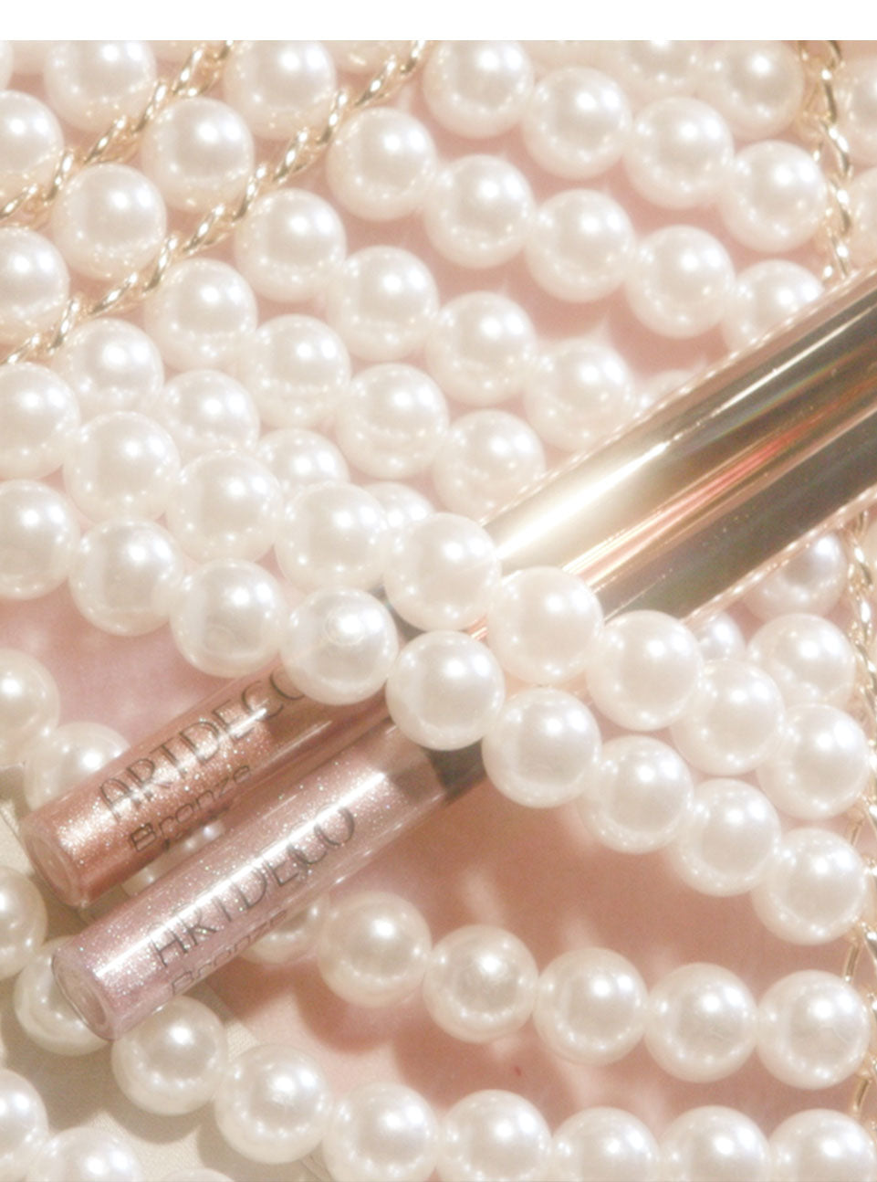 The two new Bronze Glam Eye Liners from the Mermaid Kiss Collection are beautifully placed behind some shimmering pearls. 