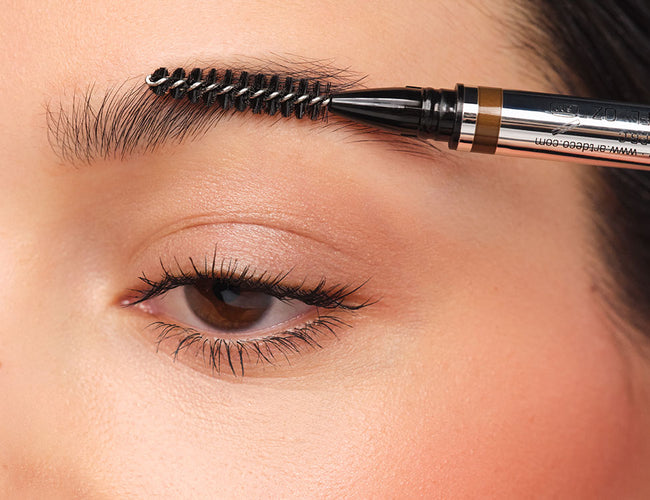 Brow hairs are brushed upward using the spoolie of the 24h Micro Brow Liquid Liner.