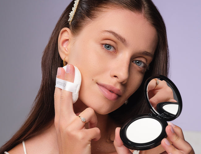 A dark-haired model applies the transparent No Color Fixing Powder with a powder puff.