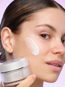 The model seen in profile, with the face cream product swatch on her cheek 