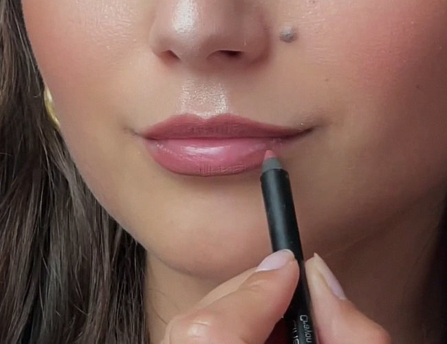 Model contours her lips with a warm, pinkish brown lip liner.