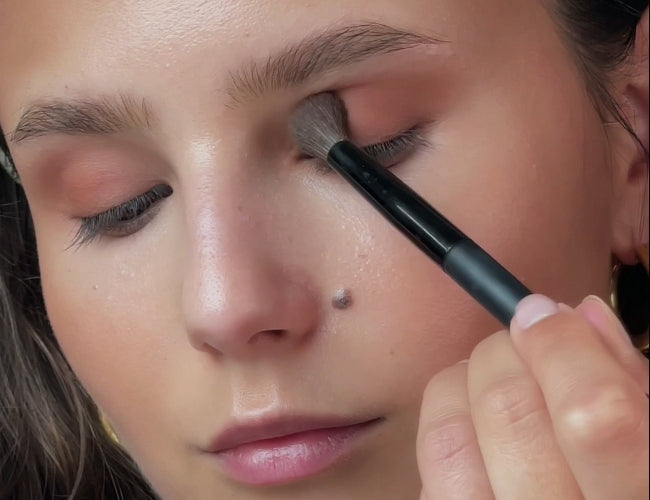 Model applies bronzer to her mobile lid for a soft latte eyeshadow look.