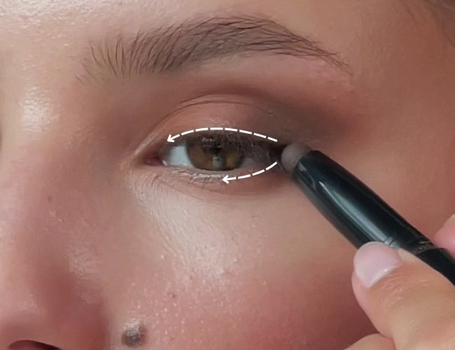 Model blends in dark, creamy eyeshadow on her upper and lower lash line for a soft, smokey fall eye look.