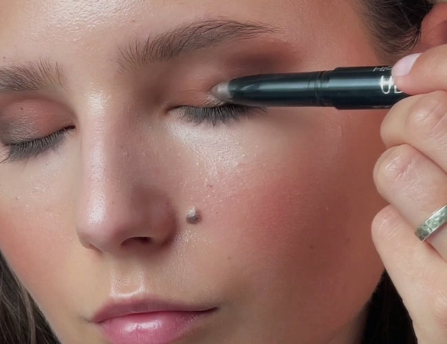 Model made up with light, creamy, shimmering brown eyeshadow on her mobile lid.