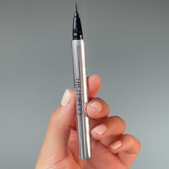 Eyeliner is held in front of the camera.