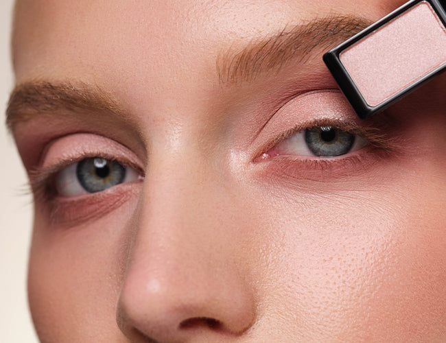 Close-up of the model’s eye, to which a soft pink eyeshadow is being applied to make the eyes appear bigger