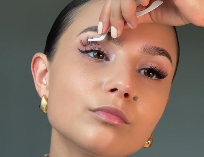 Model applies false eyelashes with an applicator.