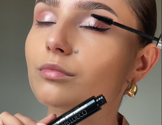 The model coats her lashes with mascara.